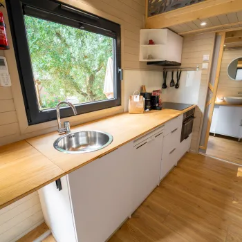Modern kitchen in a wooden interior with a window and wooden countertops.