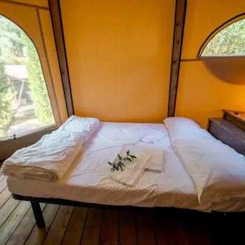 Cozy bedroom with a large bed, wooden floor, and two arched windows.