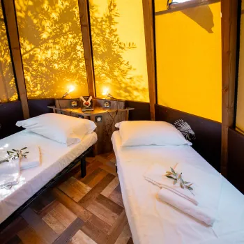Twin beds in a cozy tent with warm lighting and decorative touches.