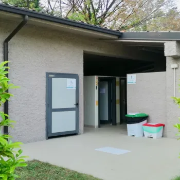 Public restroom building surrounded by green bushes.
