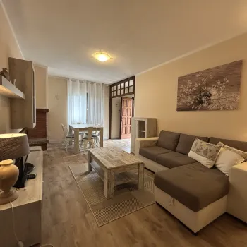 Cozy living room with beige sofa, coffee table, and dining area in the background.