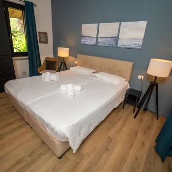 Cozy bedroom with a double bed, blue accent wall, and bedside lamps.