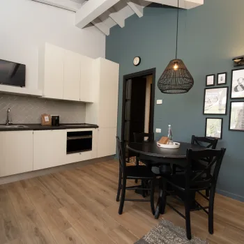Modern kitchen with dining area, teal wall, and framed pictures.