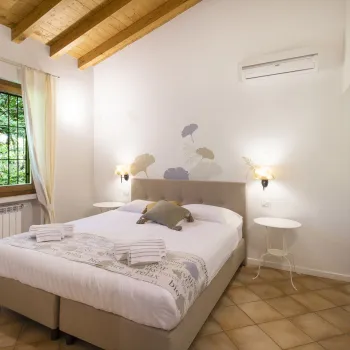 Cozy bedroom with double bed, wooden ceiling, and window with curtains.