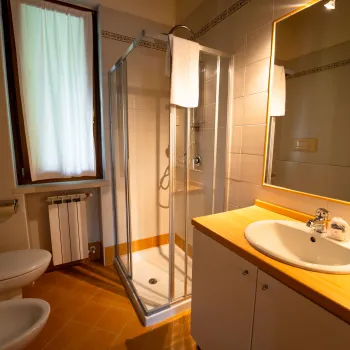 Bathroom with shower, sink, and toilet, warm lighting.