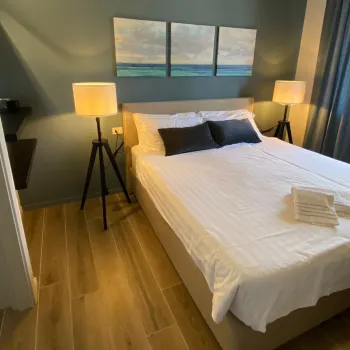 Cozy bedroom with a double bed, lamps, and artwork above.