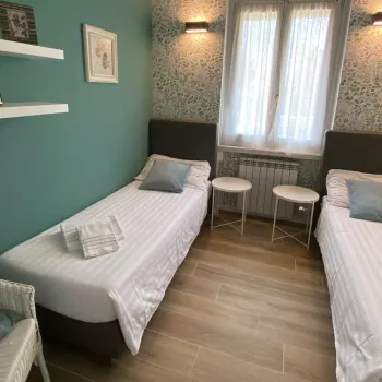 Two twin beds in a cozy, teal-accented room with soft lighting and wooden flooring.