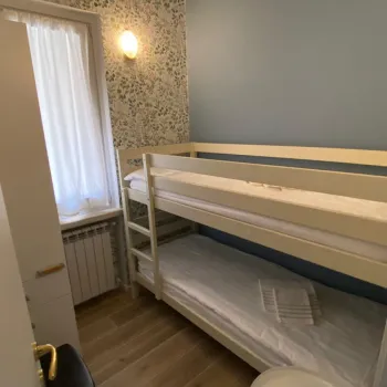Compact room with bunk beds, light blue walls, and a floral-patterned accent wall.