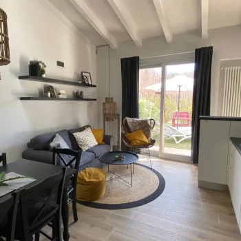 Modern living room with a grey sofa, round coffee table, and glass doors to a garden.