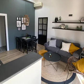 Modern living room with gray sofa, yellow cushions, and wicker chairs.