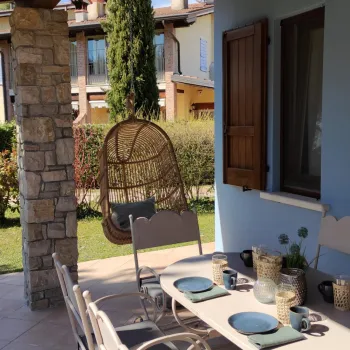 Outdoor patio with a set table and hanging chair, blue walls, and garden view.
