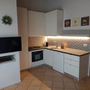 Modern kitchen corner with white cabinets, tiled backsplash, and under-cabinet lighting.
