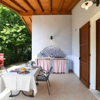 Covered patio with dining table, chairs, barbecue, and outdoor kitchen.