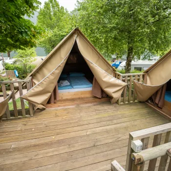 Tents on a wooden deck surrounded by trees.