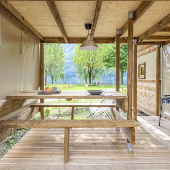 Wooden patio with picnic table, overlooking trees and a lake.