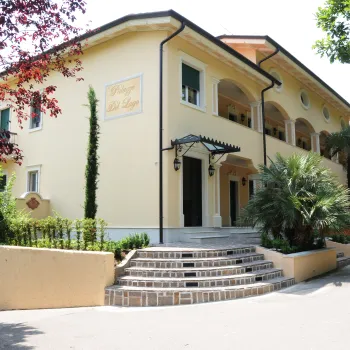 Elegant yellow villa with arched windows, surrounded by greenery.