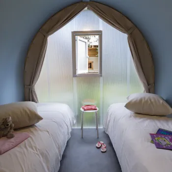 Two beds in a cozy room with a small window between them.