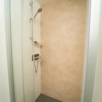 Modern shower with beige tiles and chrome fixtures.