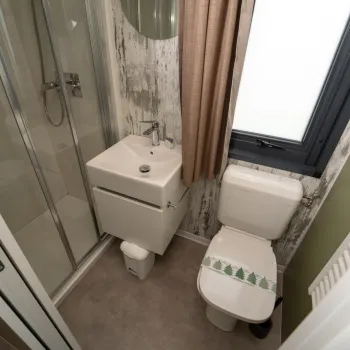Small bathroom with a shower, sink, toilet, and a large window.