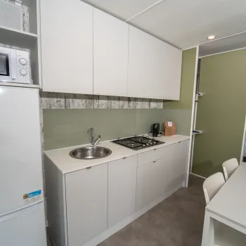Small, modern kitchenette with fridge, sink, stove, and dining table.