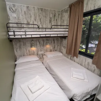 Two single beds and a bunk bed in a small room with a window.