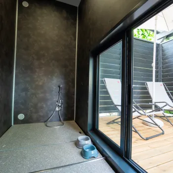 Indoor pet space with bowls, glass door to a sunny deck with lounge chairs.