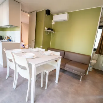 Modern kitchen and dining area with white table and chairs, green walls, compact layout.