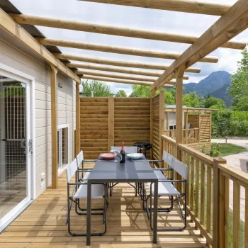 Wooden deck with table, chairs, and mountain view.
