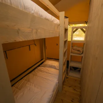 Narrow wooden room with bunk beds and soft lighting.