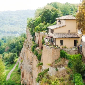 House perched on a lush cliffside, overlooking a green valley.