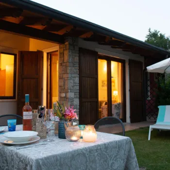 Cozy patio at dusk with lit candles on a table, lounge chairs, and an umbrella.