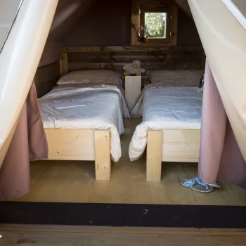 Cozy tent interior with two beds and a small window.