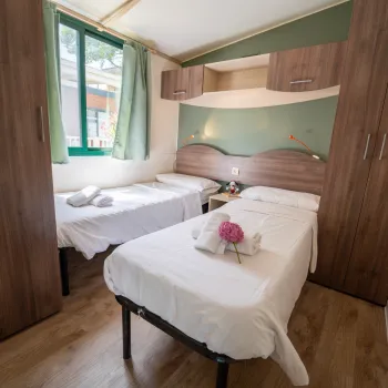 Two beds in a cozy room with wooden cabinets and green curtains.