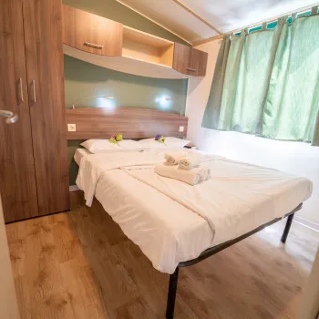 Cozy bedroom with a double bed, furniture, and green curtains.