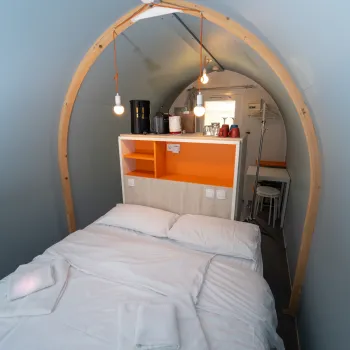 Cozy room with a bed, pendant lights, and a shelf.