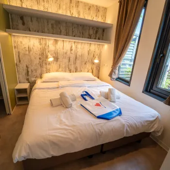 Cozy bedroom with double bed, wall lamps, and large windows.