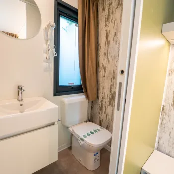 Modern bathroom with sink, toilet, and wooden accents.