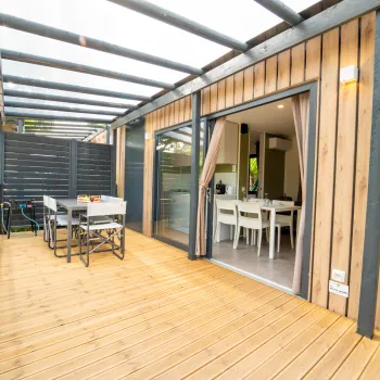 Open patio with wooden decking and outdoor dining set, leading to an indoor dining area.