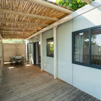 Wooden deck with table, chairs, and pergola on a sunny day.