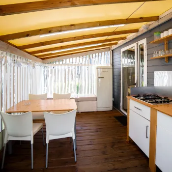 Covered patio with dining table, chairs, and kitchen.