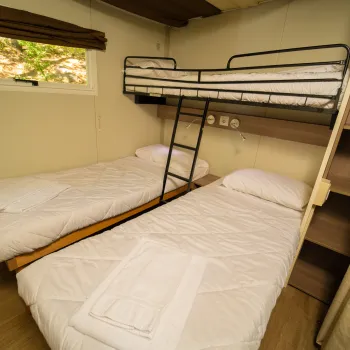 Two single beds with bed above one, in a cozy room.