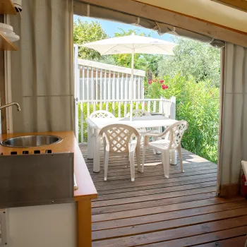 Bright veranda with white patio furniture, greenery outside, wooden floor.