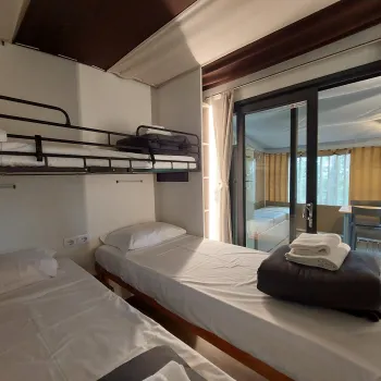 Cozy bedroom with two beds, a bunk bed, and glass doors leading to another room.