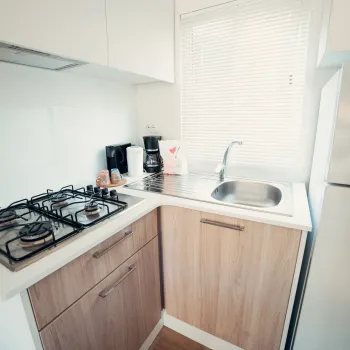 Compact kitchen with stove, sink, and white refrigerator.