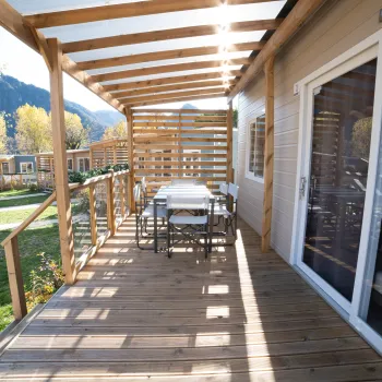 Wooden patio with dining table, chairs, and mountain view.