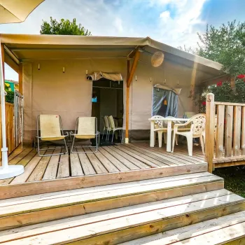 Wooden deck with chairs, table, and canopy in a sunny garden setting.