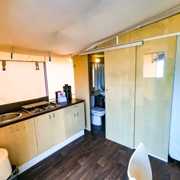 Compact kitchenette with wood cabinets, a sink, and a small stove. Adjacent bathroom area.