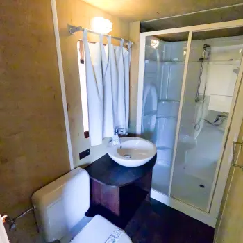 Bathroom with shower, sink, and toilet, warm lighting.