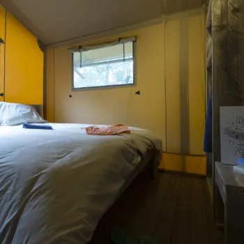 Cozy room with a double bed, yellow walls, and two small windows.