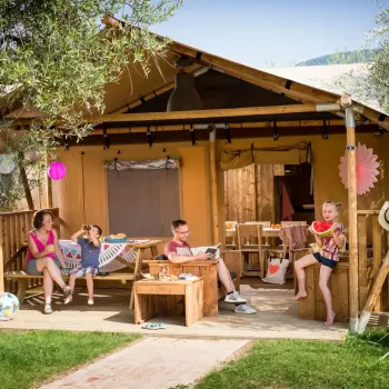 Family relaxing at a wooden campsite cabin with colorful decorations.